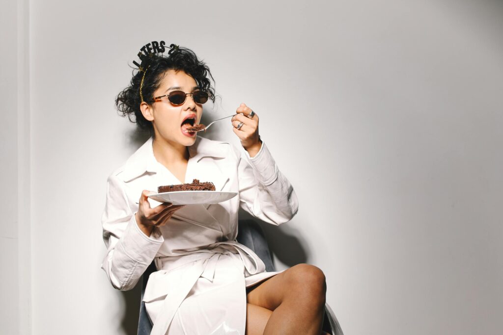 Stylish woman enjoying cake while celebrating New Year's indoors.