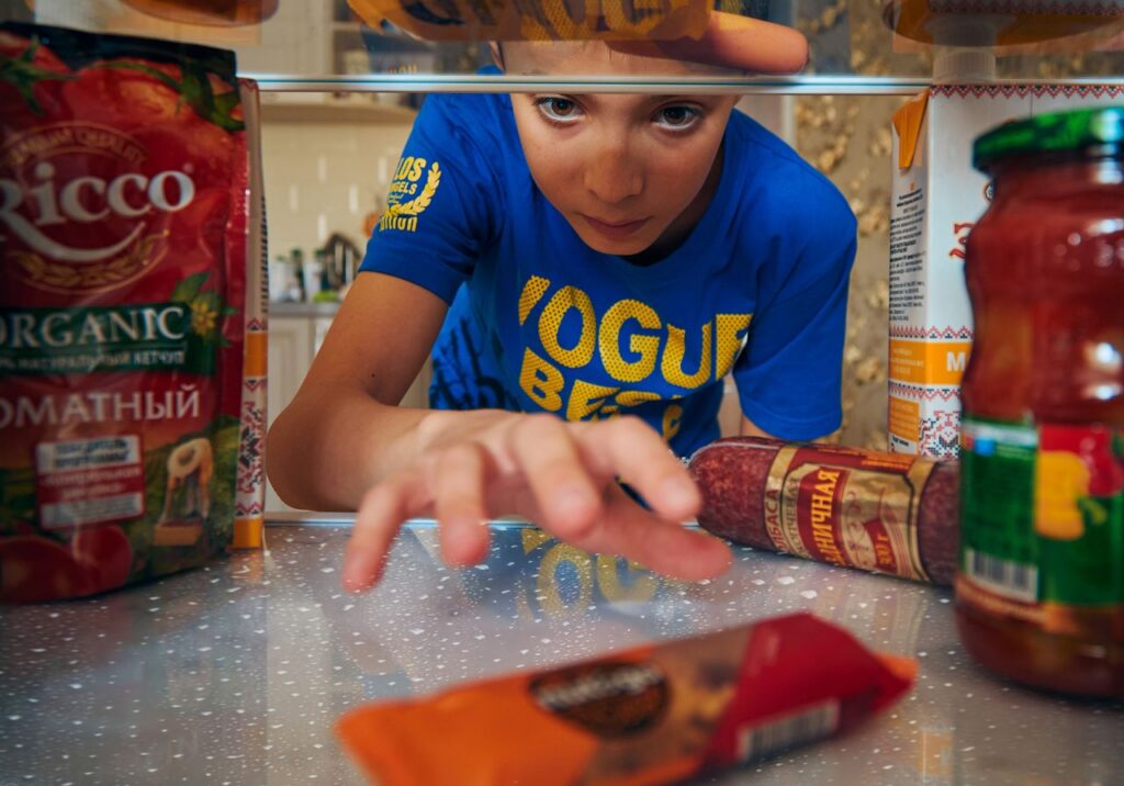 Swing Away: Golf's Secret Role in Weight Loss 4 Young boy reaching into refrigerator for a snack. Close-up view indoors.
